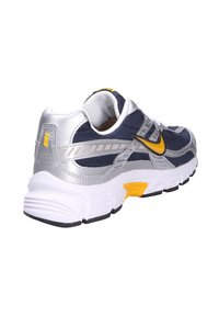 Sneakers Nike con tomaia in rete blu navy, dettagli argentati, swoosh giallo e suola bianca con decorazioni testurizzate sul tallone.