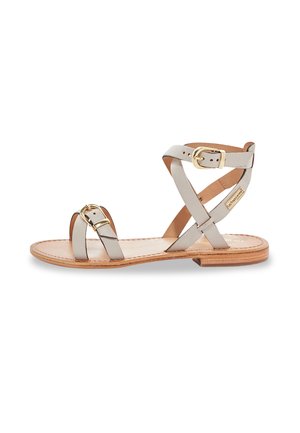 Sandal flat con cinturini in pelle grigia, design incrociato, dettagli in metallo dorato e una suola interna testurizzata di colore marrone chiaro.