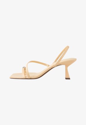 Beige sandalen met hoge hakken, dunne bandjes, een vierkante neus en een uniek hoekig hakontwerp. Glad lederen textuur met een subtiele metallic accent.