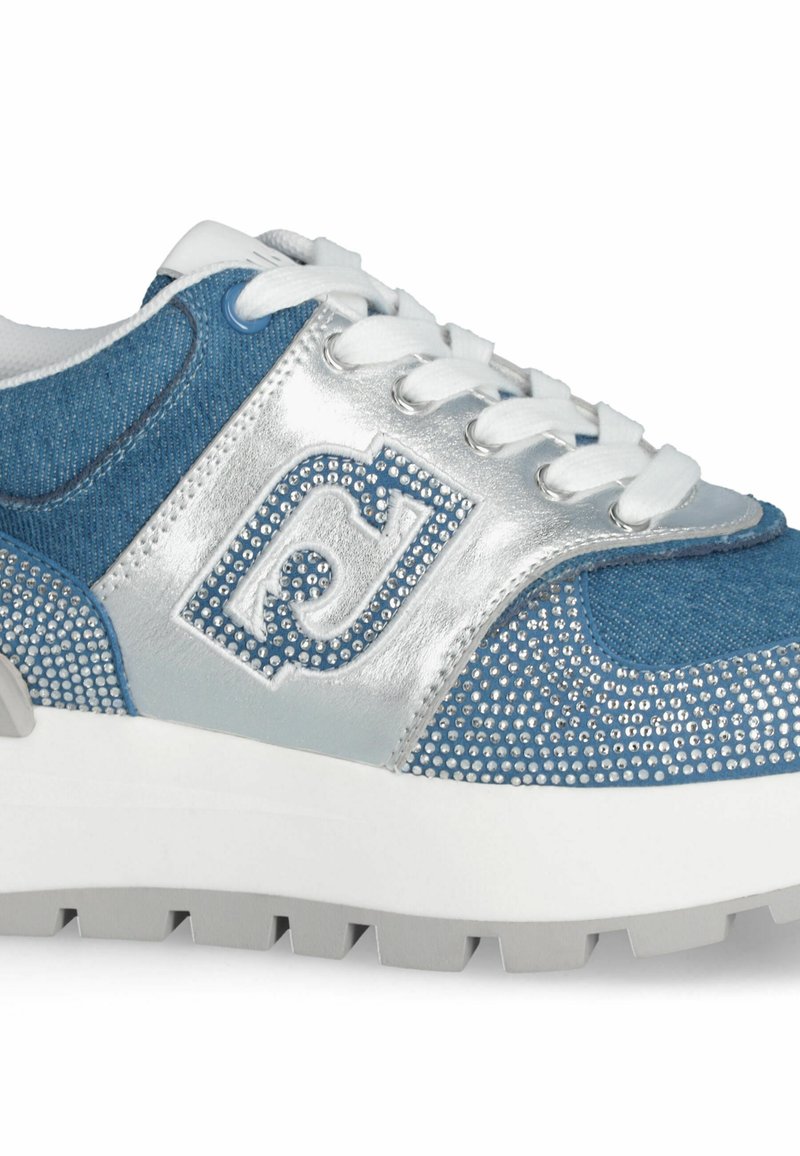 Denim- und silberne Sneaker mit einem strukturierten Obermaterial, verziert mit Strasssteinen, weißen Schnürsenkeln und einer dicken grauen Außensohle.