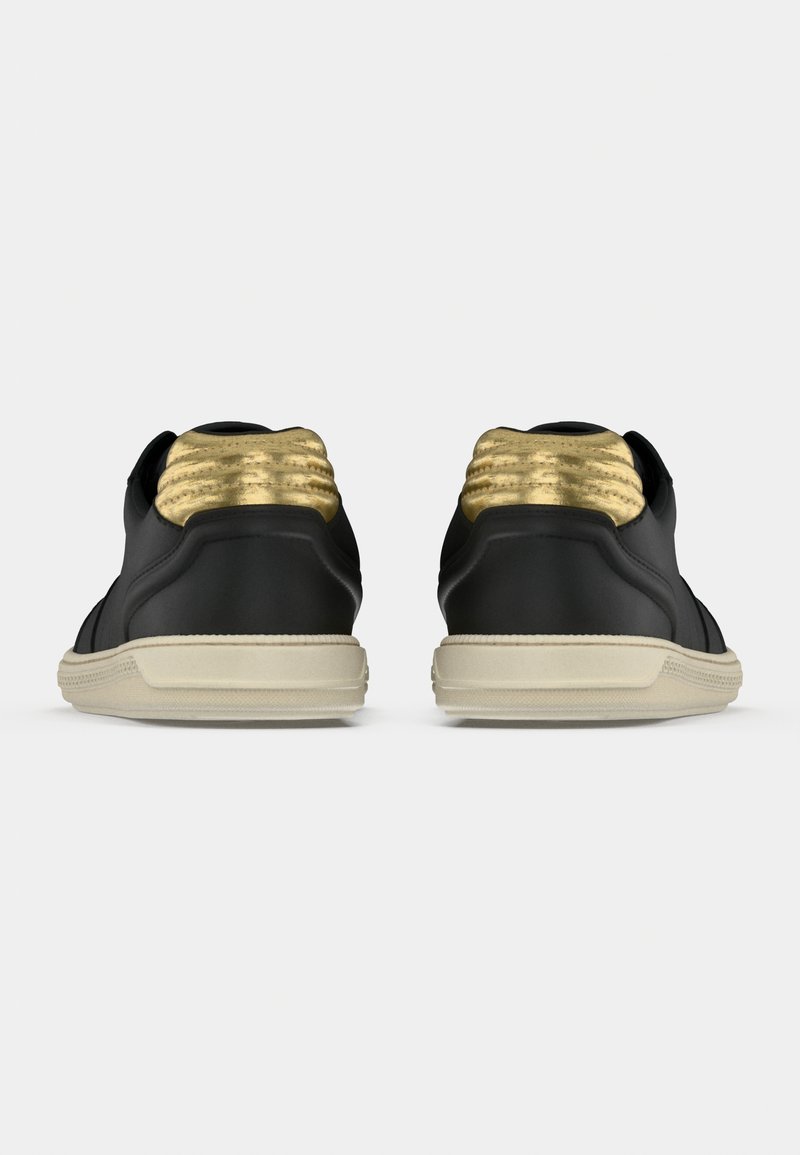 Black sneakers with gold accents, textured heel, rubber sole, and smooth leather upper. Rear view showing detailed stitching and design.