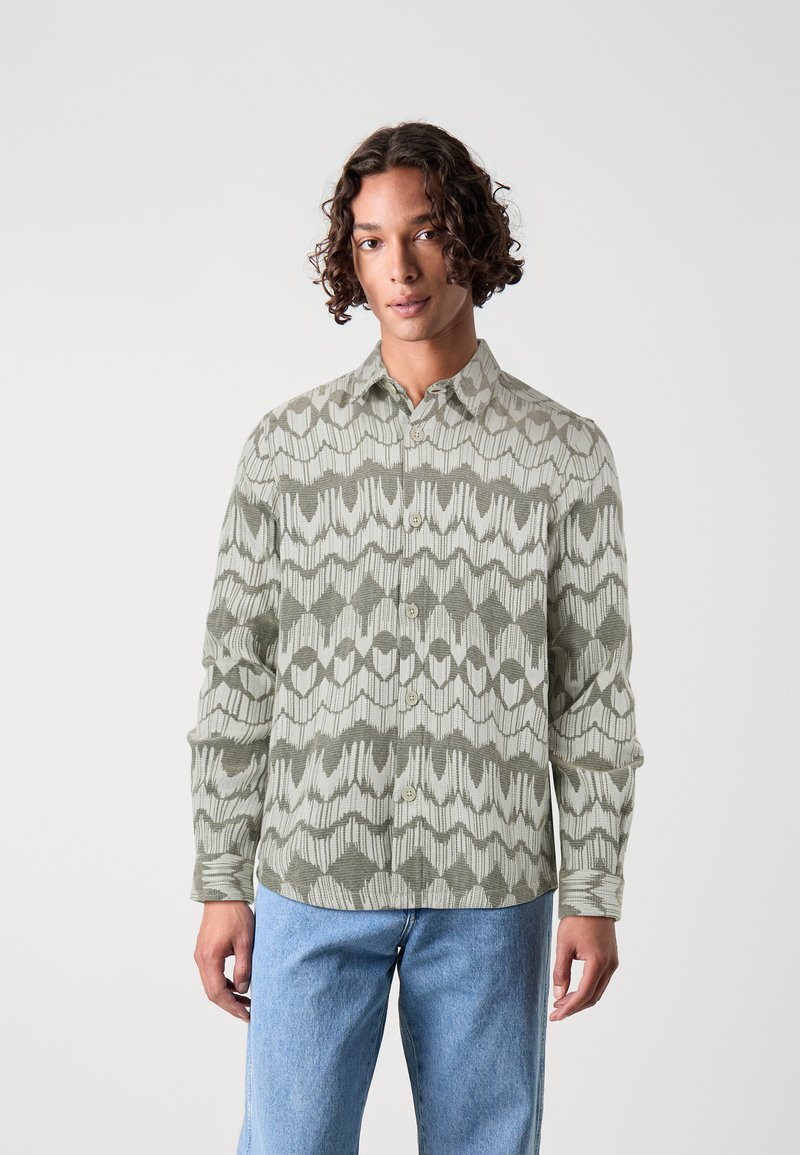 Groene shirt met een patroon en een knoopkraag, voorzien van een geweven ikatontwerp in tinten groen en crème. Lange mouwen en een relaxte pasvorm.