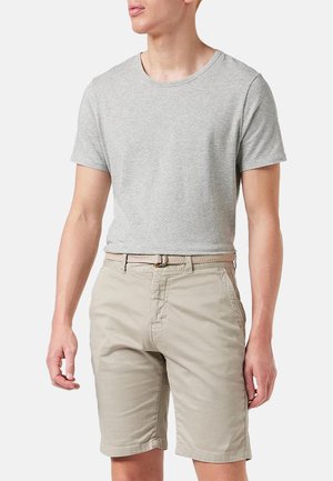 Mann trägt hellgraues kurzärmeliges T-Shirt und beige Shorts mit einem gewebten beigen Gürtel, steht mit entspannten Armen an den Seiten.