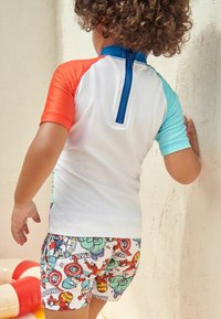 Kortærmet rash guard med røde, blå og hvide sektioner; lynlås på ryggen. Badetights med farverige Marvel superhelte-mønstre.