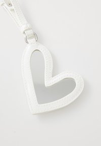 White heart-shaped mirror with a stitched border and a silver metal attachment. Smooth texture with a reflective surface in the center.