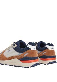 Zapatillas de gamuza marrón y azul marino con acentos en beige claro, que cuentan con un cuello acolchado, detalle del logotipo y una franja naranja en la suela.
