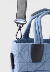 Τσάντα χειρός σε ανοιχτό μπλε χρώμα με ραμμένη επένδυση, επενδεδυμένες λαβές, μαύρο τριγωνικό δερμάτινο επίθεμα και αποσπώμενο μαύρο κλιπ στο ιμάντα ώμου με λογότυπο.