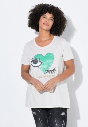 Camiseta de manga corta color crema con un corazón verde, un gráfico de un ojo guiñando y la palabra "Feliz" en letras doradas.