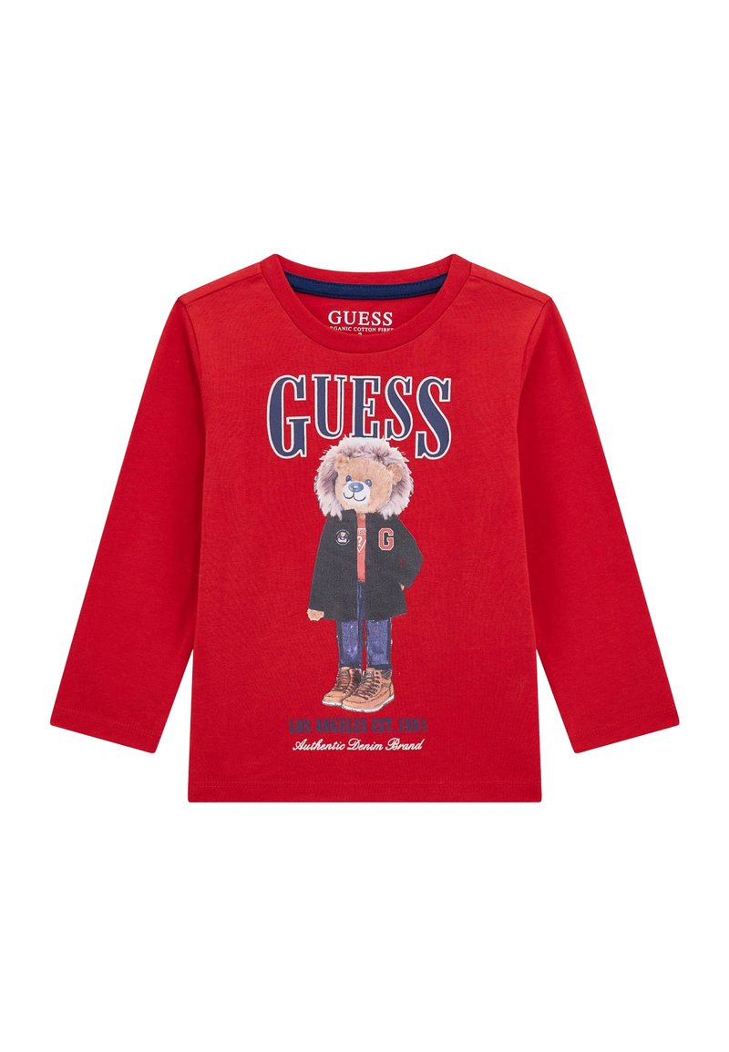 Crvena majica dugih rukava od organskog pamuka, sa grafikom medvjeda u jakni i čizmama, sa natpisom "GUESS" u podebljanim slovima.