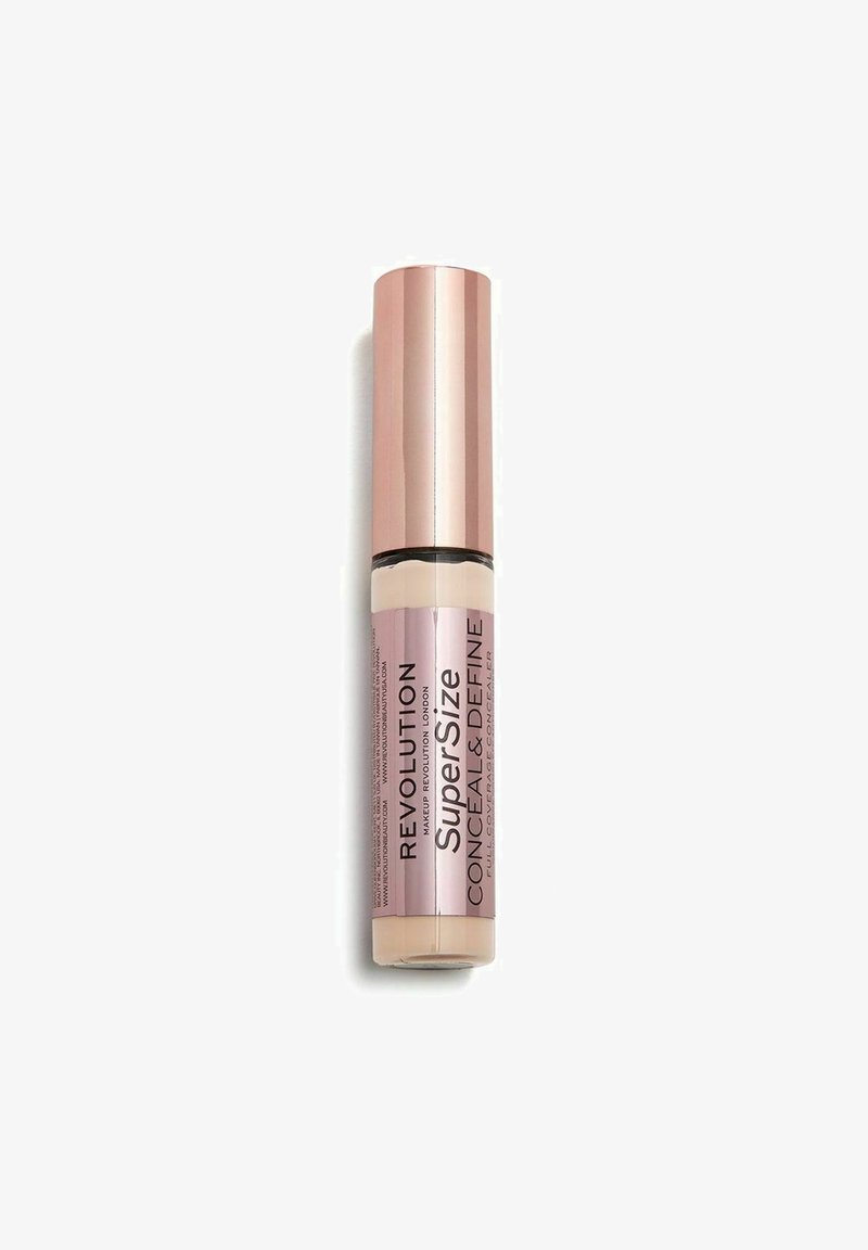 Revolution SuperSize Conceal & Define i et cylindrisk rør i rosaguld med et klart vindue, der viser det cremede beige produkt indeni.
