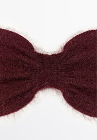 Fascia lavorata a maglia color bordeaux con una morbida e pelosa texture, caratterizzata da una forma a fiocco nella parte anteriore e un centro a coste per dare struttura.