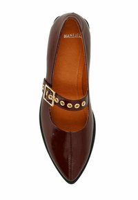 Chaussure plate en cuir verni bordeaux avec un bout pointu, dotée d'une sangle décorative avec une boucle dorée et des accents circulaires. L'intérieur est doublé d'une couleur beige.