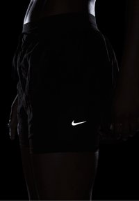 Pantalones cortos deportivos negros con una superficie texturizada, que presentan un logotipo de swoosh blanco de Nike en el muslo izquierdo, cintura ajustable con cordón y un corte holgado.