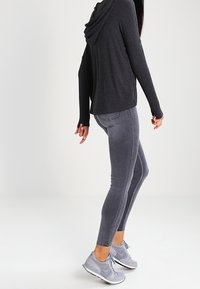 Grå hoodies i mjukt tyg i kombination med grå slim-fit jeans och grå träningsskor, med en minimalistisk design.