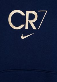 Námořnická mikina s krémovým textem "CR7" a logem Nike v jednoduchém, tučném písmu; vyrobena z měkké tkaniny s hladkou strukturou.