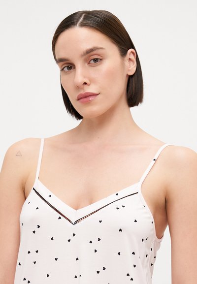 Svijetlo ružičasti top s crnim uzorcima srca, podesive naramenice, i V-izrezom s kontrastnim detaljem.