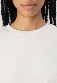 Cream-colored, crew-neck sweatshirt made of soft cotton. Features a smooth texture and a relaxed fit with subtle stitching details.