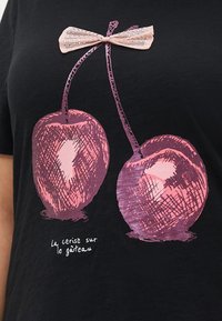Svart t-skjorte med et grafisk motiv av to rosa kirsebær med en sløyfe. Under teksten står det "la cerise sur le gâteau" i hvitt. Mykt bomullsstoff.