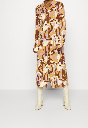 Langærmet, knaplukket midikjole med abstrakt brunt, beige og lavendelmønster, båret med knælange off-white støvler.