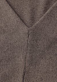 Tessuto grigio a maglia con design a V, caratterizzato da una superficie testurizzata e rigata. Notevole per il suo aspetto morbido e tessuto.