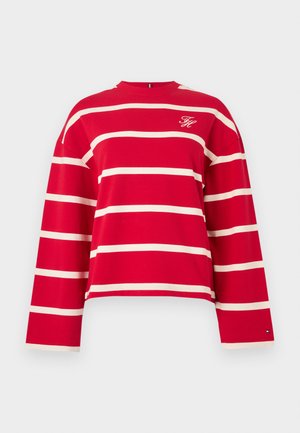 Punane pika varrukaga topp kreemja horisontaalse triipudega, ümmarguse kaelusega ja väikese logoga rinnal. Pehme puuvillane kangas.