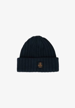 Donkerblauwe gebreide beanie met ribbelstructuur en een omgeslagen rand. Bevat een rechthoekige bruine leren patch met een logo ontwerp.