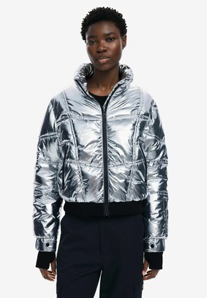 Giacca a vento argentata con colletto alto, chiusura con zip e polsini elastici. Materiale testurizzato e lucido con un design cropped e dettagli neri.