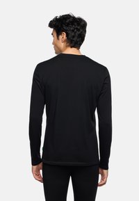 Zwart langemouwen shirt met een ronde halslijn, gemaakt van een gladde stof. Het heeft minimale stiksels en een klein groen label aan de zoom.