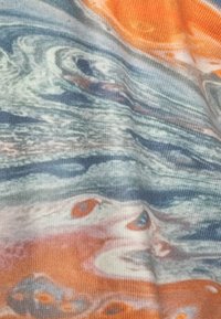 Mehrfarbiger Stoff mit wirbelnden Mustern in Blau, Grün, Orange und Weiß. Weiche Textur mit einem leichten Erscheinungsbild.