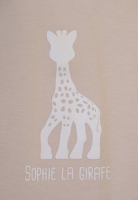 Design di Sophie la Giraffe, silhouette bianca di una giraffa con macchie visibili, su uno sfondo beige texture, con il nome sotto.