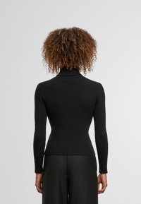 Czarny sweter typu golf z prążkowanego materiału, z długimi rękawami, dopasowany fason i wysoki golf. Gładka tekstura z minimalnymi zdobieniami.