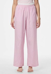 Roosa ja valge triibuline lai jalad püksid, millel on elastne värvel ja sile kangas, koos lamekontsadega sandaalidega.