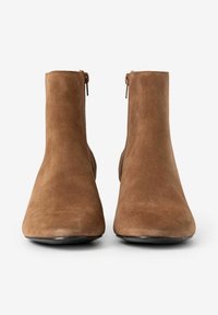 Braune Wildleder-Stiefeletten mit glatter Textur, einem zulaufenden Design, seitlichen Reißverschlüssen und einer runden Spitze. Schwarze Außensohle.