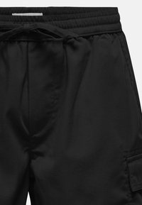 Sorte shorts med elastisk talje og snor. Indeholder sidelommer og en cargolomme, lavet af et glat, let stof.