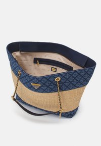 Grand sac fourre-tout avec une partie supérieure en synthétique matelassé bleu et un fond en paille tissée, des accents en métal doré et une poche zippée à l'intérieur.