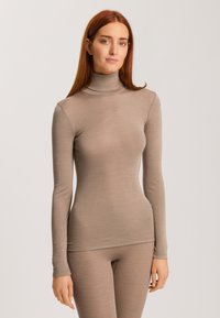 Långärmad polo i mjukt beige tyg, kroppsnära design, slät textur och ribbat halsdetalj. Matchas med matchande byxor.