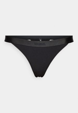 String noir en tissu lisse et extensible avec une taille brillante et marquée. Design minimaliste sans motifs supplémentaires.