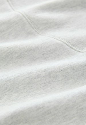 Tessuto in cotone grigio chiaro con una texture morbida, caratterizzato da sottili variazioni di colore e dettagli nei punti, che creano una superficie liscia.