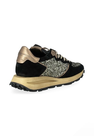 Black and gold athletic shoe featuring a suede upper with glitter accents, a padded collar, and a textured sole for traction.