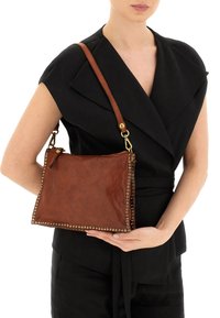 Borsa a mano in pelle marrone con dettagli borchiati dorati, forma rettangolare, tracolla regolabile e chiusura con cerniera. Texture liscia.