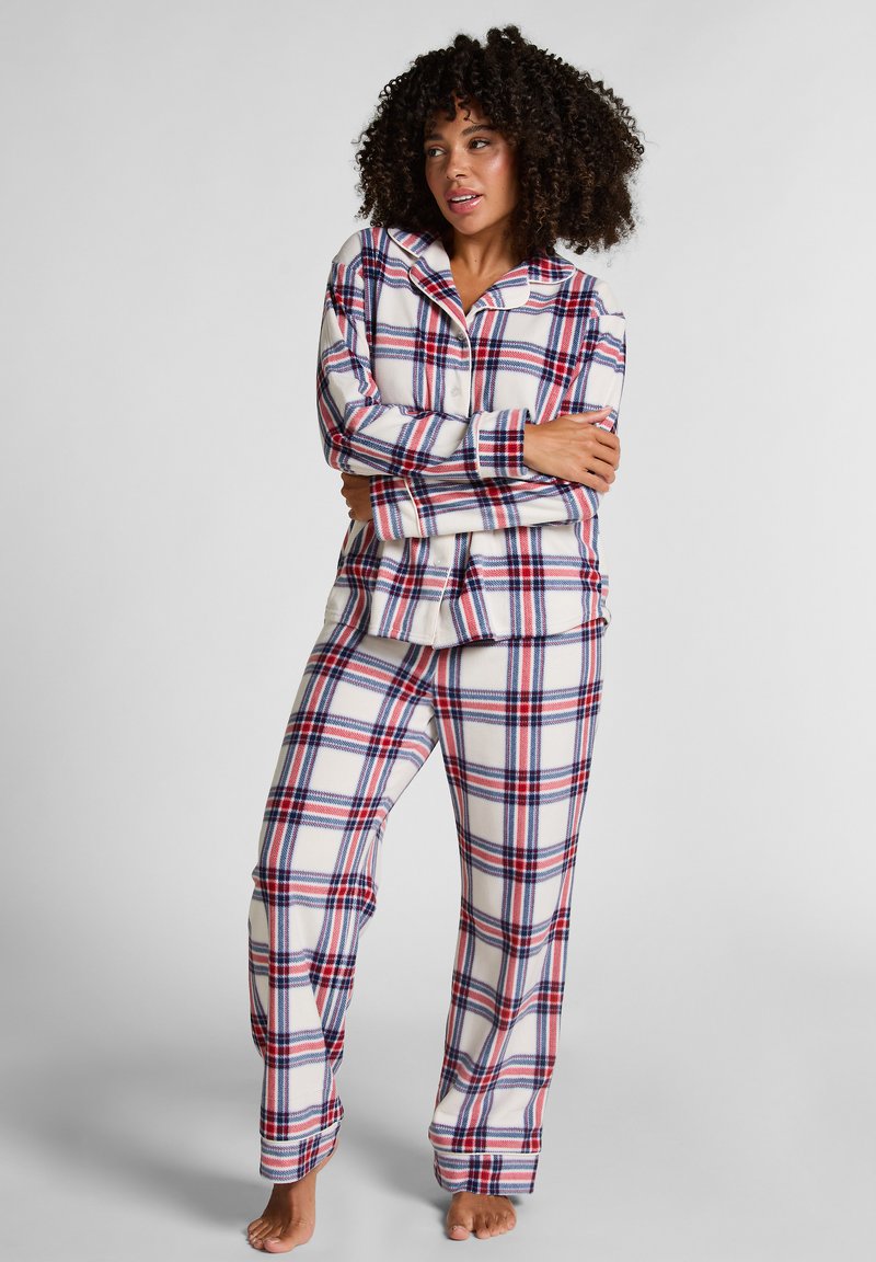 Flanellen pyjamastel met een witte basis, voorzien van een rood en blauw plaidpatroon, lange mouwen, een geknoopte shirt en bijpassende broek. Zachte textuur.