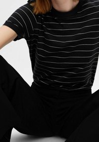 Schwarz kurzärmliges Shirt mit weißen horizontalen Streifen, rundem Halsauschnitt und weichem Material, kombiniert mit schwarzen geraden Hosen.