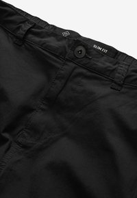 Svarta slim-fit byxor med en slät yta, med knäppning, platt front och subtila söm-detajler.