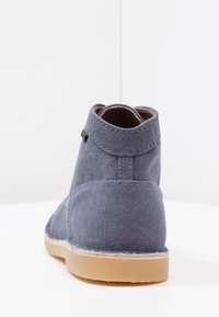 Botte cheville en toile bleue avec un embout rond, des coutures contrastantes et une semelle en caoutchouc naturel ; présente un col doux au niveau de la cheville.