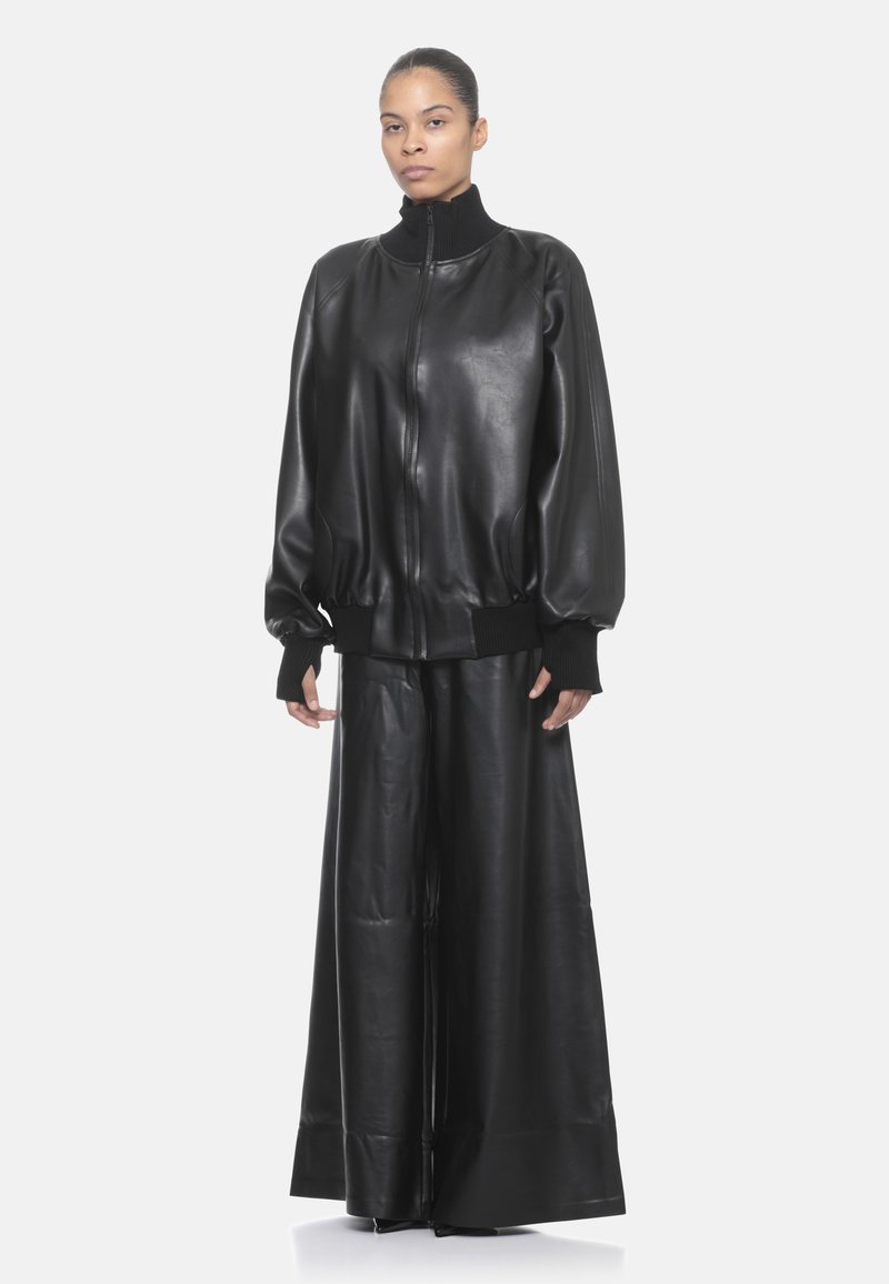 Giacca bomber in pelle nera con colletto alto, polsini a coste e pantaloni in pelle a gamba larga abbinati, caratterizzati da una texture liscia e un design minimalista.