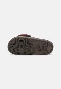 Nike cipőtalp sötétszürke színben, körkörös mintázattal, barázdákkal a tapadásért és egy kiemelkedő Nike logóval. Jellemzője a lapos, széles forma.