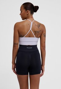 Zwarte high-waisted shorts met ribbelstructuur en logo. Gepaard met een lichtgrijze, strapless sporttop in een aansluitend ontwerp.