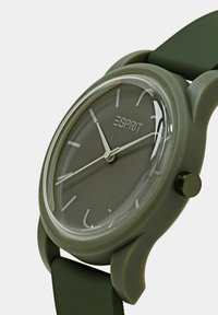 Grøn silikonestrapsur med en rund grå urskive, sølvdetaljer, kontrasterende timemarkører og en gennemsigtig glasvisning.
