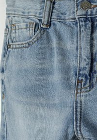 Svijetloplave traperice s klasičnim dizajnom s pet džepova, vidljivim šavovima i metalnim dugmetom za zatvaranje u struku.