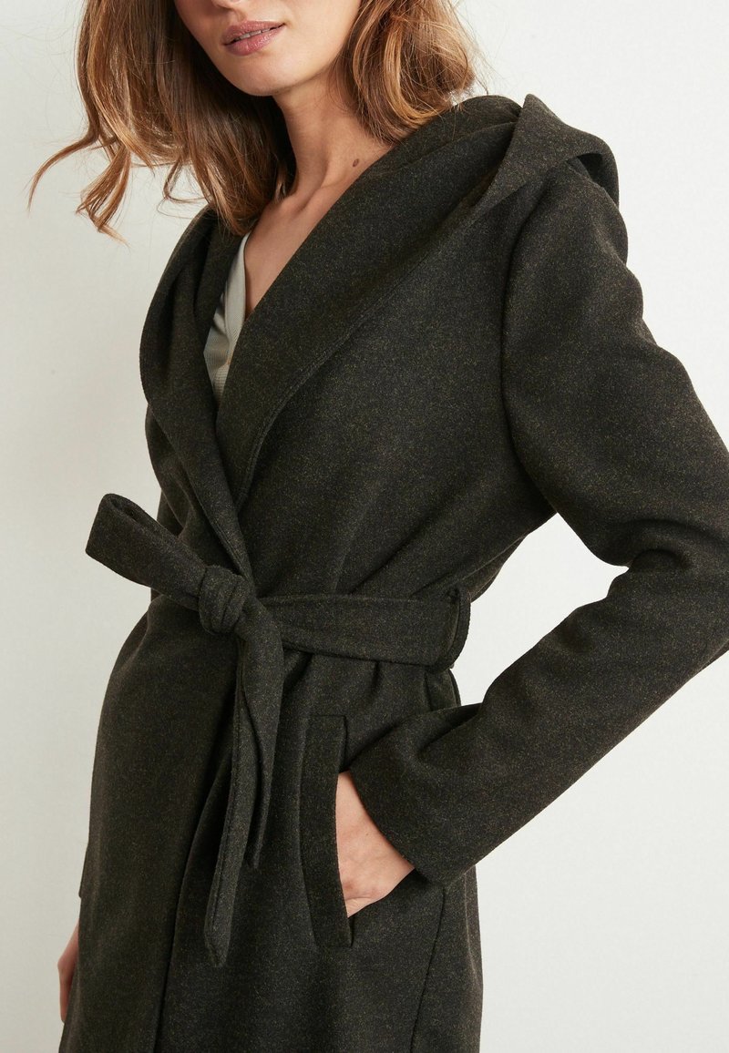 Mørkegrøn uldblandingsfrakke med sjalskrave, bælte i taljen og sidelommer. Har en blød tekstur og skræddersyet design.